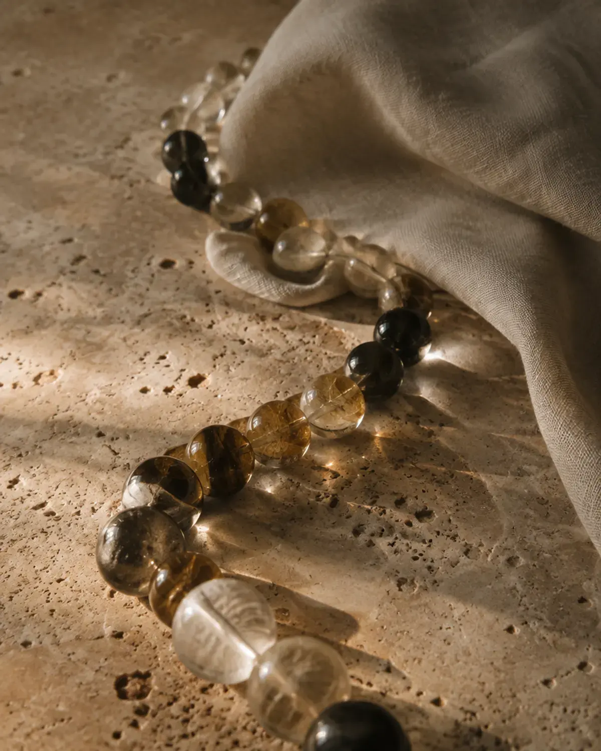 Glass beads arranged in a soft spiral on travertine stone
